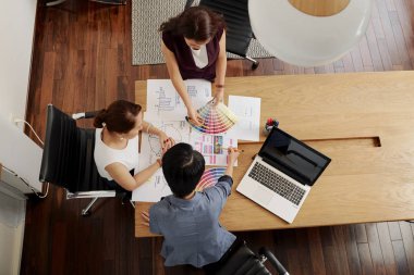 Ofiste ekip birlikte renkli desenler ile masada çalışan tasarımcıların grup üst görünümü