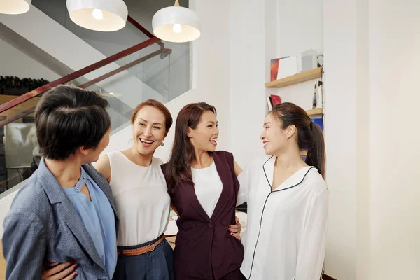 オフィスに立ちながら抱き合い 話し合うアジアのビジネスウーマンのグループ — ストック写真