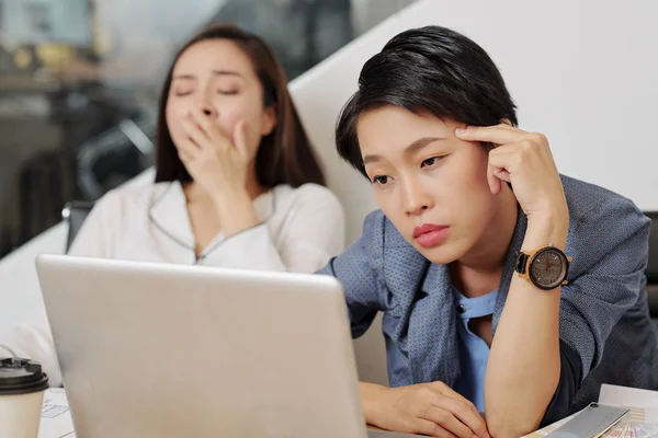 亚洲年轻女商人坐在她的工作场所前笔记本电脑 看着显示器 她看起来疲惫和无聊 — 图库照片