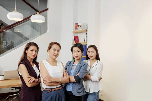 亚洲严肃美丽的女商人站在一排 双臂交叉 看着相机在现代办公室的肖像 — 图库照片