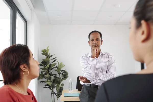 インドの真面目なビジネスマンがオフィスでのビジネスミーティングで話しているパートナーの話を聞いている — ストック写真
