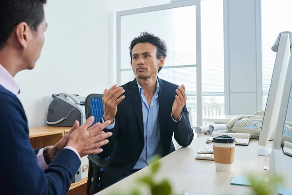 成年亚裔男子在现代办公室与商业伙伴讨论工作时打手势 — 图库照片