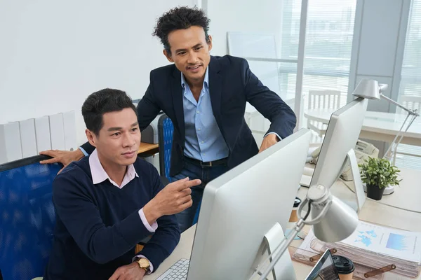 Dos Hombres Asiáticos Mirando Monitor Computadora Con Datos Financieros Mientras — Foto de Stock