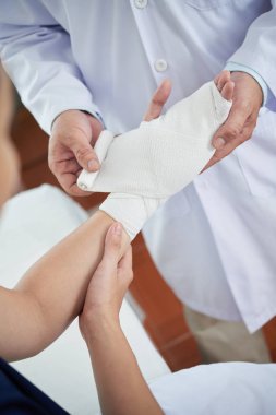 Doktor Genç hastanın yaralı eline bandaj uygulama