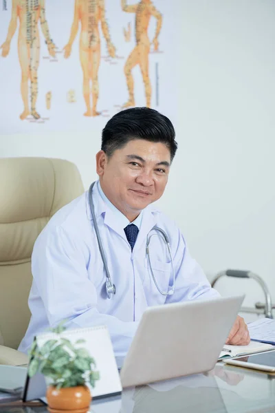 Retrato Quiroprático Vietnamita Sorridente Sentado Mesa Seu Escritório — Fotografia de Stock