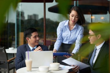 Onun iş arkadaşları toplantı yaşıyorsanız kafe masaya belgeleri getiren güzel genç işletme kadın
