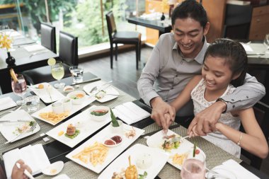 Onlar restoranda öğle yemeği yerken onun çanak ile kızına yardım gülümseyen baba