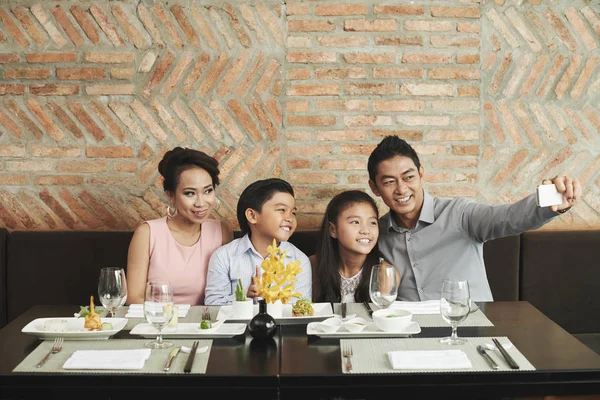 快乐的亚洲家庭在餐厅的餐桌上拍照 — 图库照片