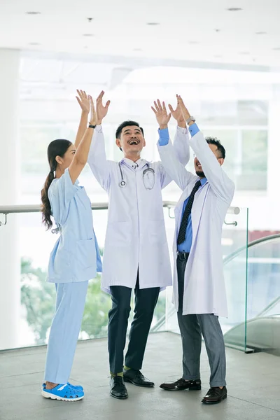 Team of happy excited doctors celebrating something in office hall