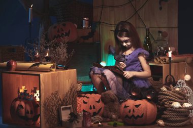 Kedi kostüm kız Halloween süslemeleri büyüteç ile bir kitap okuma