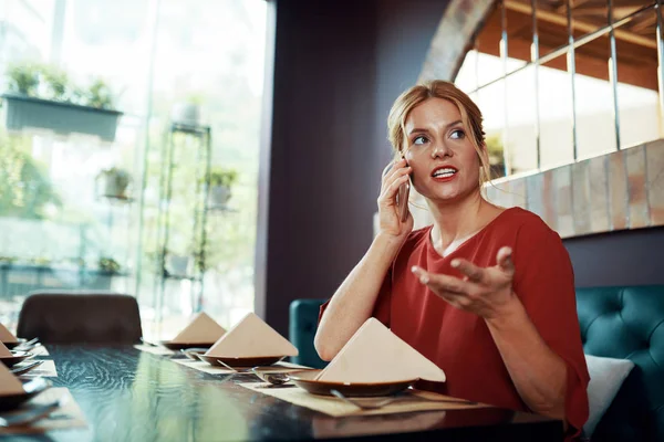 Schöne Junge Emotionale Frau Sitzt Restauranttisch Und Telefoniert Wenn Sie — Stockfoto