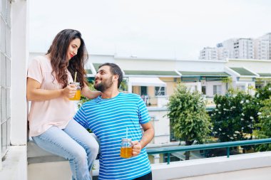 Onların otel odasının balkonunda duran ve lezzetli limonata içme genç Hintli çift sarılma