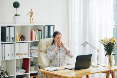 Gün boyu ofis masasında çalıştıktan sonra boynunda ağrı veya migren ağrısı çeken iş kadını