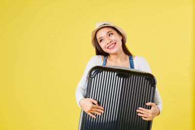 Panama şapkalı, bavuluna sarılan pozitif rüya gibi genç Vietnamlı kadının portresi 