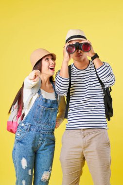 Şaşırmış genç Asyalı kadın meraklı bir şey işaret ve dürbün ile bakmak için erkek arkadaşı soran