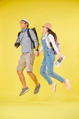Bilet ve dijital kamera el ele, sarı izole ile turist genç Vietnamlı çift Atlama