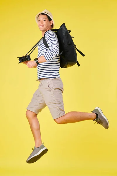 黄色のスタジオの背景にバックパックとデジタルカメラを持つ若いアジアの旅行者の空中ショット — ストック写真