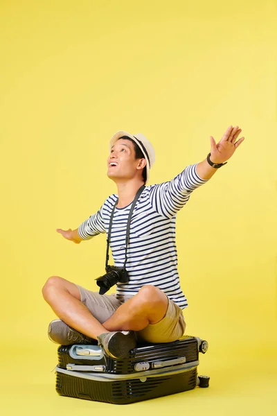 Szczęśliwy Młody Azjatycki Człowiek Siedzi Walizka Rozkłada Ramiona Gdy Marzy — Zdjęcie stockowe