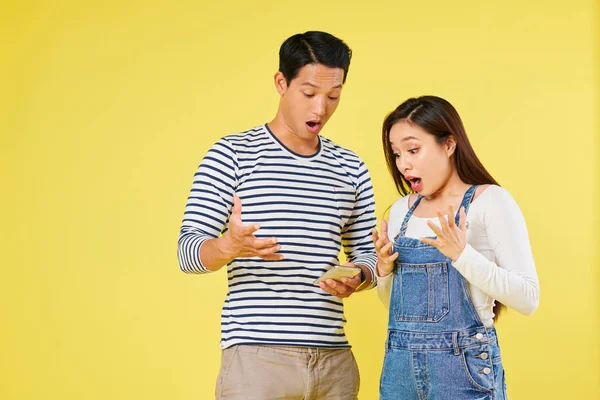 情感兴奋或震惊的年轻越南夫妇在智能手机屏幕上阅读通知 — 图库照片