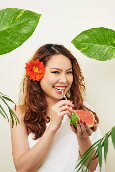亚洲模特喝西瓜汁从吸管和微笑的镜头与绿叶周围的白色背景的肖像 — 图库照片