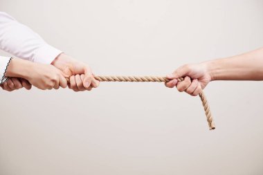 Beyaz arka plana karşı bir kişiye karşı ipi çeken insanların yakın çekim