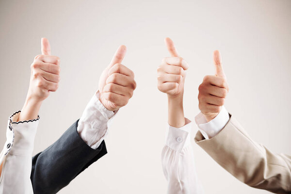 Close-up of group of business people showing thumbs up and satisfied of their work isolated on white background