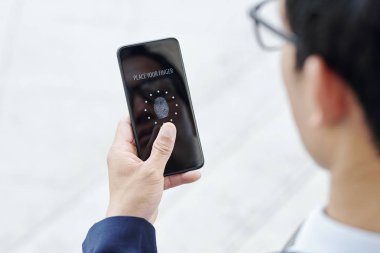 Uygulamalara erişmek için akıllı telefonuna parmak basan işadamı