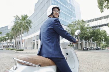Pozitif genç Vietnamlı işadamı scooter açık havada sürme kask giyiyor