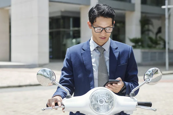 Junger Vietnamesischer Unternehmer Sitzt Auf Roller Und Checkt Sms Auf — Stockfoto