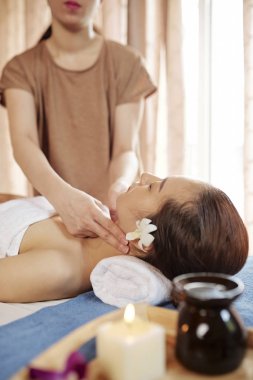 Rahatlatıcı spa prosedürü nden sonra yatakta dinlenen kadın müşteri nabzına dokunan kadın masör
