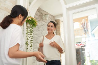 Spa salonuna gelen gülümseyen genç kadın ve girişin yakınında onunla buluşan kadın