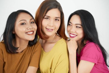 Üç Asyalı kız arkadaş birbirlerine gülümseyerek kucaklayan ve kamera poz portresi
