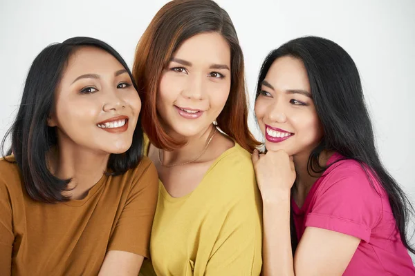 Üç Asyalı kız arkadaş birbirlerine gülümseyerek kucaklayan ve kamera poz portresi