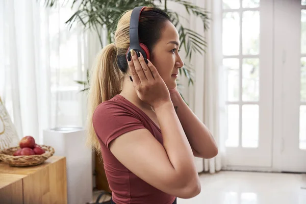 年轻的漂亮亚洲女人戴着耳机在家里听音乐 — 图库照片