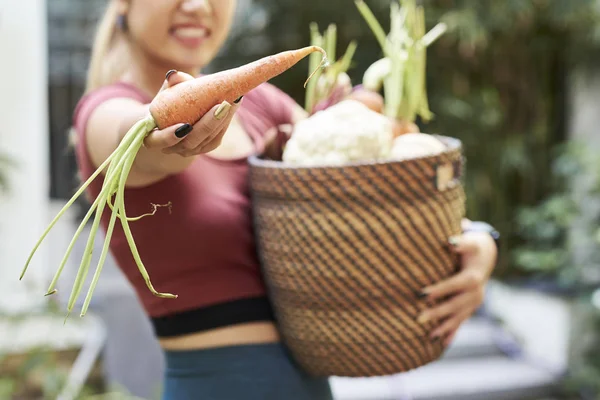快乐的年轻女子与篮子蔬菜 她收获 显示新鲜的胡萝卜 选择性的焦点 — 图库照片