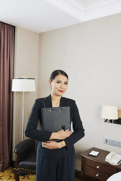 Portrait of Asian young businesswoman in black suit standing with folder in her hand and working as a manager of the hotel