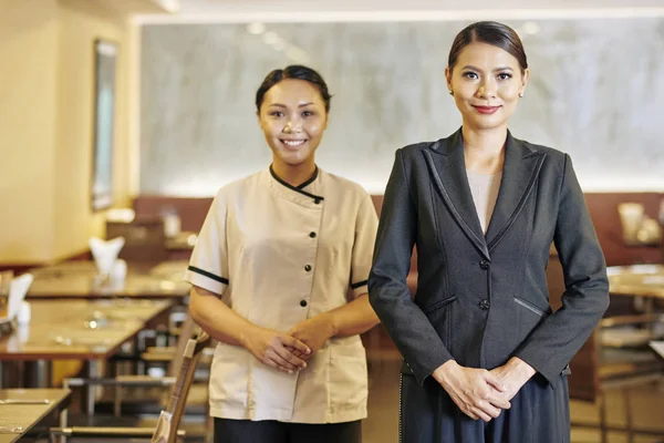 身着西装的亚洲经理和身着制服的女服务员在餐厅的摄像机前站在一起微笑的肖像 — 图库照片