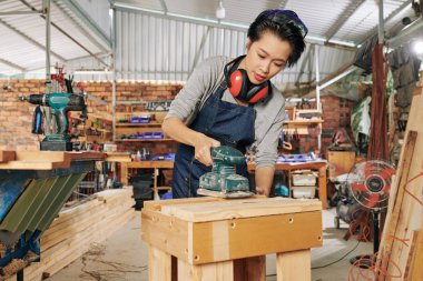 Profesyonel kadın marangoz o atölyede yapılan masanın ahşap yüzey parlatma