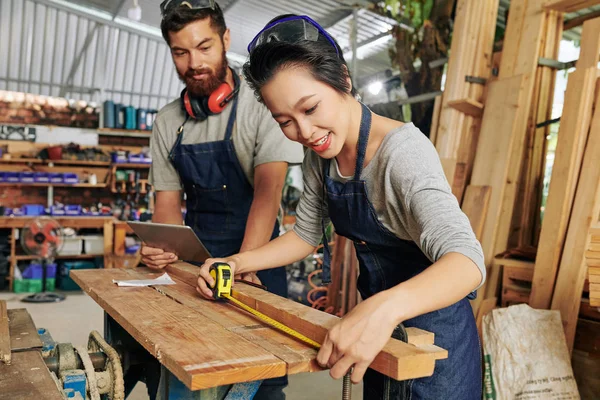 Positieve Vrouwelijke Timmerman Denim Schort Meten Houten Plank Met Meetlint — Stockfoto