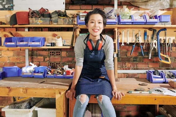 快乐漂亮的年轻越南女木匠坐在家具车间的工作台上 — 图库照片