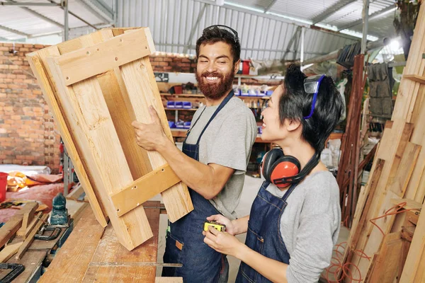 快乐的多民族木匠团队讨论他们制作的新家具 — 图库照片