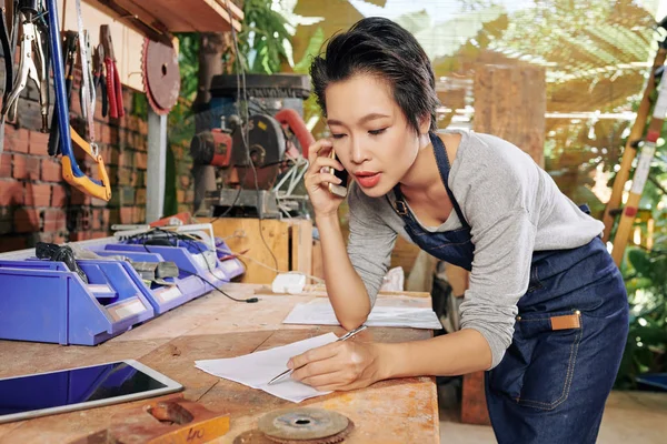 Młoda Kobieta Stolarz Rozmawia Telefon Zapisuje Szczegóły Zamówienia — Zdjęcie stockowe