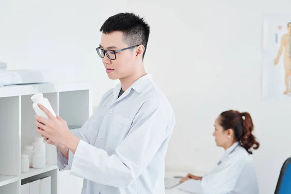 Junger Vietnamesischer Arzt Liest Kontraindikationen Auf Behälter Mit Tabletten Und — Stockfoto