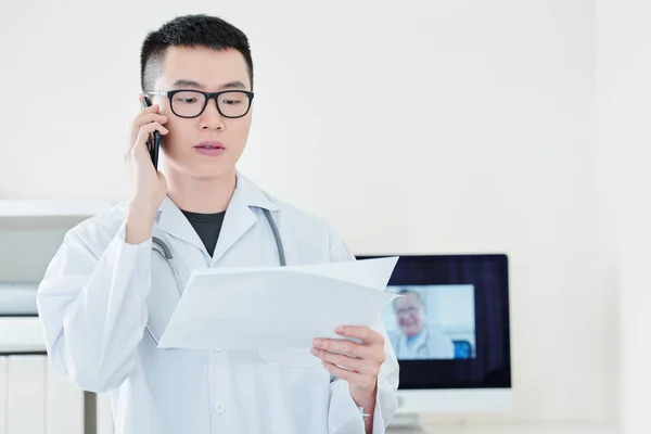 Giovane Medico Vietnamita Serio Documento Lettura Parlando Telefono Raccontando Diagnosi — Foto Stock
