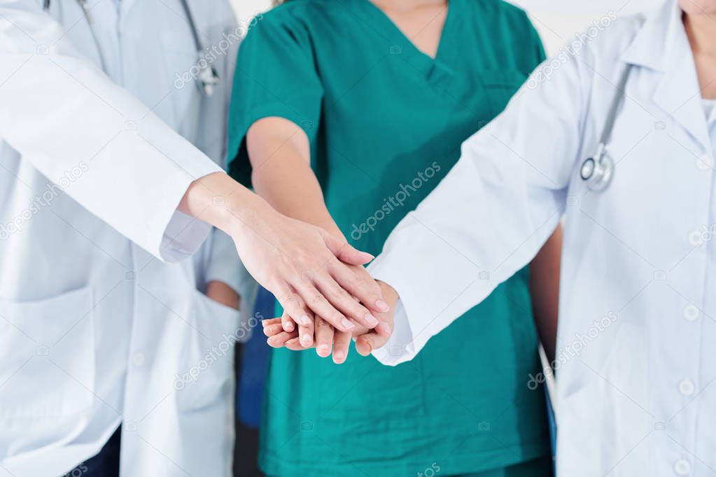 Surgeon and his assistants stacking hands to support each other before difficult surgery