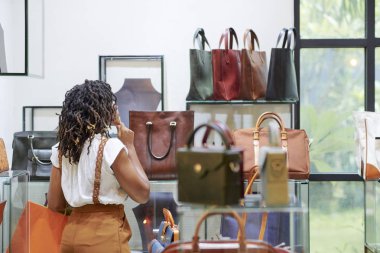 Güzel saç modeli ayakta ve dükkanda deriden çanta seçimi ile Afrikalı kadının Arka görünümü