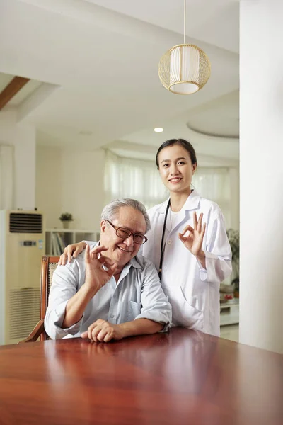 亚洲女医生和亚洲资深男子的肖像在镜头前微笑 并显示好标志一起在医院 — 图库照片