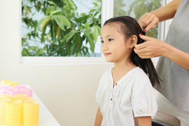 Kuaför kuaför kuaför de saçlarını fırçalarken Ayna önünde oturan Asyalı küçük kız