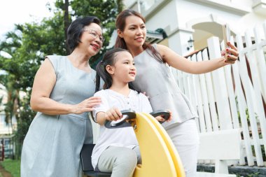 Asyalı aile nesli arka bahçelerinde birlikte oynarken cep telefonu selfie portre yapma