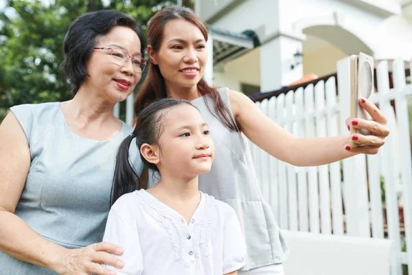 亚洲家庭的三个母亲的女儿和祖母在手机上摆姿势自拍肖像 而花时间在户外 — 图库照片
